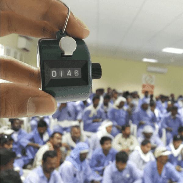 Attendance counter held in front of a large group of workers during a safety training session, reflecting transforming worker safety and well-being.