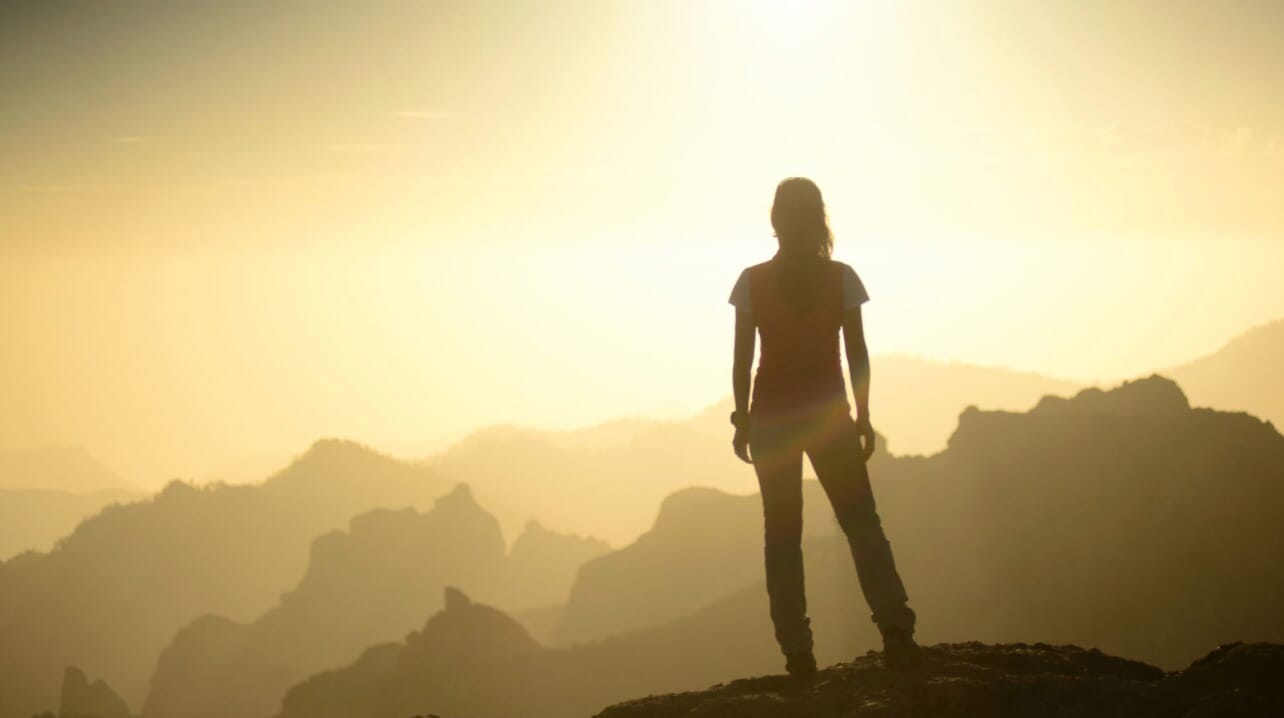 Person-sillouhetted-on-mountain-looking-into-distance
