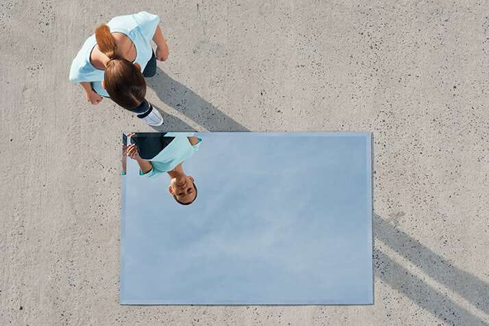 woman-looking-into-mirror-on-the-ground