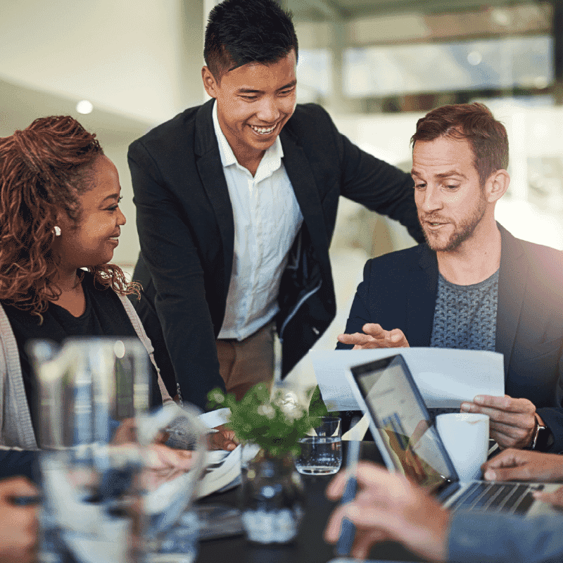 Diverse team collaborating around a table and reviewing materials during a session focused on building confident change leaders.